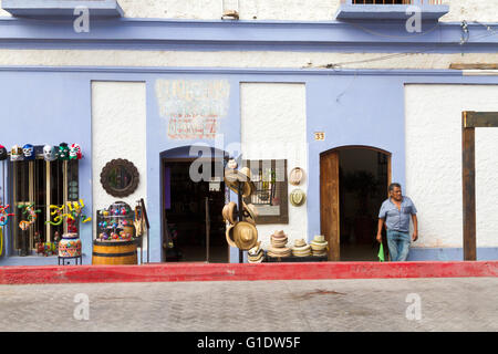 Un messicano proprietario del negozio si erge nel vano della porta del suo negozio di souvenir in Todos Santos, Baja, Messico con gli elementi visualizzati per la vendita. Foto Stock