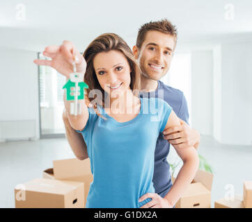Giovane coppia sorridente mantenendo le loro nuove chiavi di casa, immobili e concetto di rilocazione Foto Stock