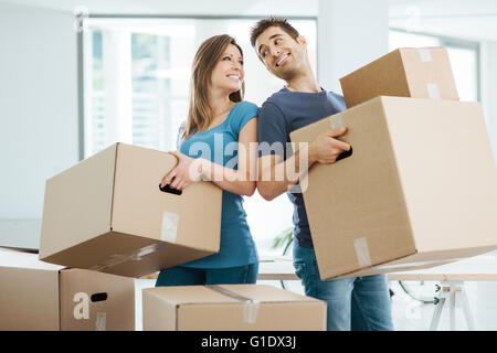 Coppia felice fissando ogni altri occhi e scatole di trasporto nella loro nuova casa Foto Stock