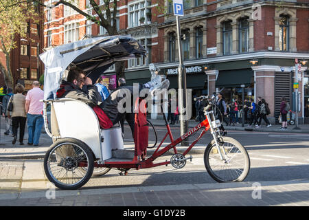 In rickshaw drivers prendere un periodo di riposo e attendere per i clienti al di fuori del Palazzo del Teatro su Cambridge Circus nel West End di Londra, Regno Unito Foto Stock