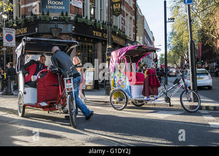 In rickshaw drivers prendere un periodo di riposo e attendere per i clienti al di fuori del Palazzo del Teatro su Cambridge Circus nel West End di Londra, Regno Unito Foto Stock