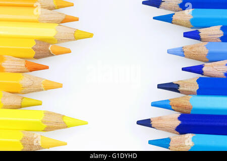 Matite colorate di diverse tonalità di colore blu e giallo con spazio di copia si trovano una contro l'altra lungo i bordi dell'immagine Foto Stock