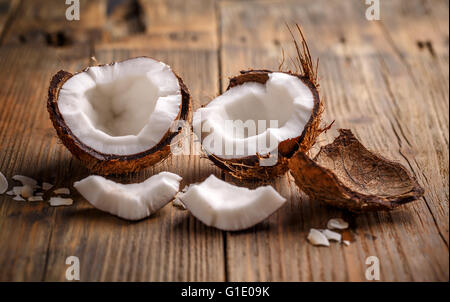 Il Cocco tagliato a metà su sfondo di legno Foto Stock