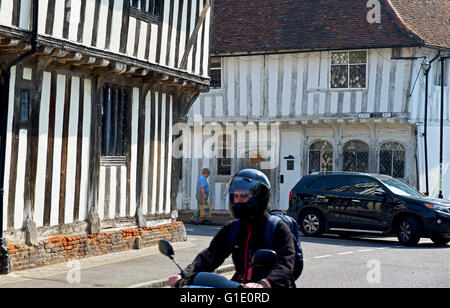 Di auto e moto nel villaggio di Lavenham, Suffolk, Inghilterra, Regno Unito Foto Stock