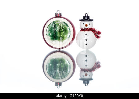 Snowglobe con albero di Natale all'interno con pupazzo di neve su sfondo bianco, Riflessione Foto Stock