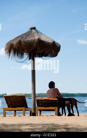 Petzow, Germania. 13 Maggio, 2016. Illustrazione - un uomo si siede su una sdraio sulla spiaggia con il suo cane accanto a lui a Caputh lido e si affaccia sul Lago Schwielowsee in Petzow, Germania, 13 maggio 2016. La qualità delle acque di tutti i 251 ufficiale dei laghi balneari è eccellente secondo il ministero dei consumatori di Brandeburgo. Foto: Klaus-Dietmar Gabbert/dpa/Alamy Live News Foto Stock