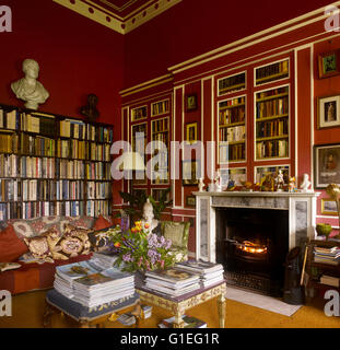 Cairness House, Fraserburgh, Aberdeenshire, Scozia. Vista della libreria con divano e caminetto. Gli scaffali il rivestimento delle pareti. Foto Stock