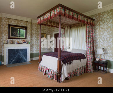 Cairness House, Fraserburgh, Aberdeenshire, Scozia. Vista di una spaziosa e tradizionale camera da letto con un letto a baldacchino e la carta da parati con motivi geometrici. Quadro appeso sopra il camino. Foto Stock