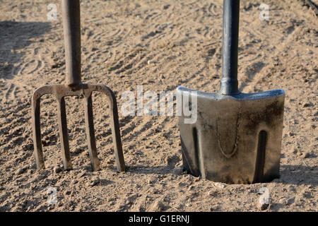 Forcone e vanga infissa a terra closeup. Foto Stock