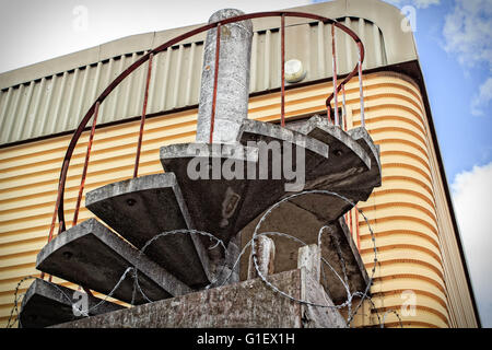 Scale a chiocciola con ringhiera in ferro una volta che uso come una via di fuga in caso di incendi su un metallo abadon magazzino Foto Stock