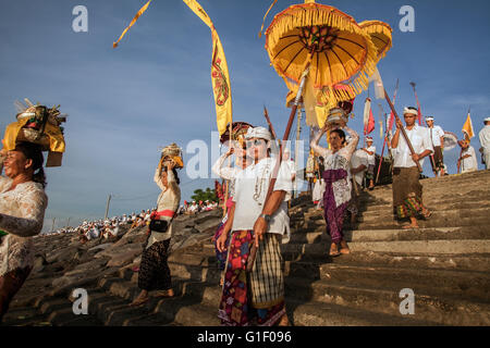 Processione di Balinese dell'indù portando bandiere, striscioni e ombrelloni presso la cerimonia Melasti durante il Balinese nuovo anno Foto Stock