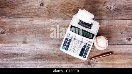 Vista aerea di una vecchia carta calcolatrice, utilizzato baseball e antichi penna su rustiche tavole in legno. Foto Stock