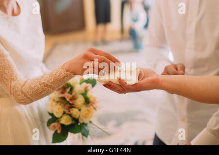 Sposa felice prendendo cuscino bianco witn anelli di nozze durante la registrazione Foto Stock