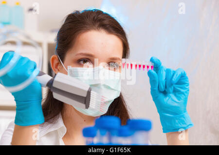 Modello rilasciato. Tecnico femminile utilizzando multipipette in laboratorio. Foto Stock