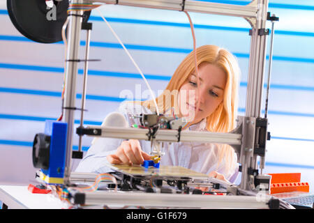 Modello rilasciato. Tecnico femminile utilizzando una stampante 3d. Foto Stock