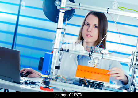 Modello rilasciato. Tecnico femminile utilizzando una stampante 3d. Foto Stock