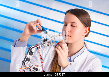 Modello rilasciato. Femmina ingegnere elettrico lavorando sul braccio robotico. Foto Stock