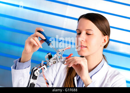 Modello rilasciato. Femmina ingegnere elettrico lavorando sul braccio robotico. Foto Stock