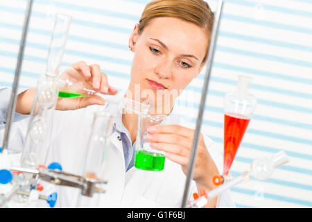 Modello rilasciato. Farmacia femmina versando chemicals in vetreria di laboratorio. Foto Stock