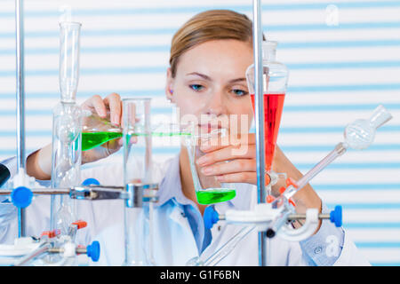 Modello rilasciato. Farmacia femmina versando chemicals in vetreria di laboratorio. Foto Stock