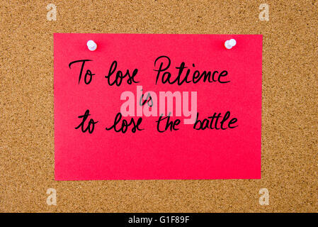 Carta rossa nota con il testo scritto a mano a perdere la pazienza viene a perdere la battaglia imperniata sulla bacheca di sughero con thumbtacks bianco Foto Stock