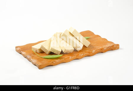 Blocco a fette di tofu fresco sul bordo di taglio Foto Stock