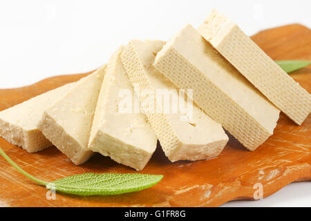 Blocco a fette di tofu fresco sul bordo di taglio Foto Stock