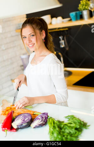 Piuttosto giovane donna tagliare le verdure nella cucina moderna Foto Stock