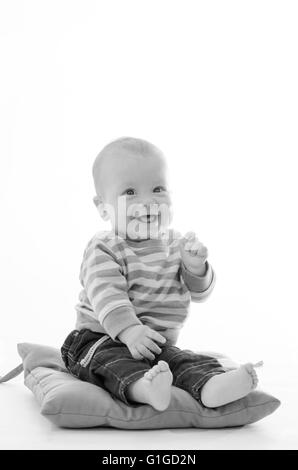 Ragazzo dolce bambino sorridente sedersi sul cuscino verde isolato su bianco Foto Stock