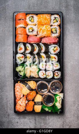 Varie selezione di sushi in nero il confezionamento di vassoio su pietra grigia sfondo, vista dall'alto. Vista la composizione. Il giapponese e il cibo asiatico Foto Stock