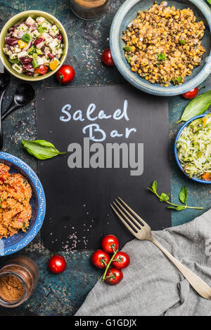 Salad bar con vari salutari insalate vegetariana piatto, forg e lavagna, vista dall'alto il telaio. Iscrizione salad bar su blan Foto Stock