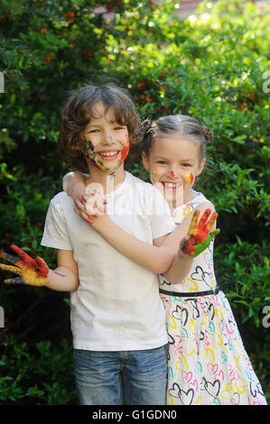 Ragazza abbracciando un ragazzo, le loro facce e le mani di vernice Foto Stock