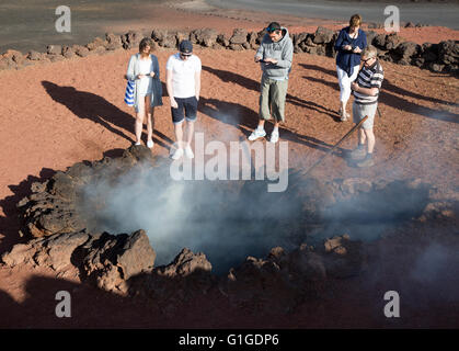 I turisti stand intorno al fuoco nel piccolo cratere, Parque Nacional de Timanfaya, parco nazionale, Lanzarote, Isole Canarie, Foto Stock