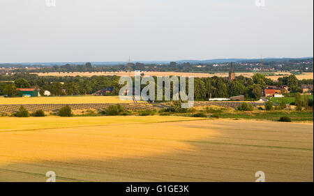 Angolo di alta vista sui campi per un grande pannello solare park fornendo energia rinnovabile con un villaggio in background. Foto Stock