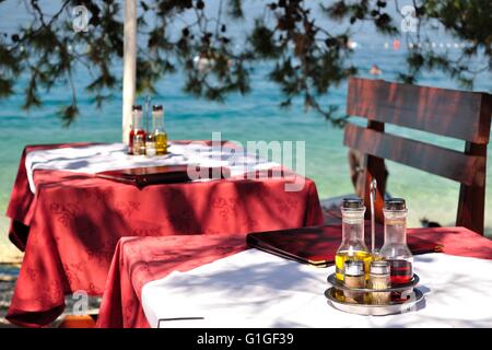 Impostazione tabella con bottiglie di olio di oliva e aceto al Tropical Beach Restaurant, Croazia Foto Stock