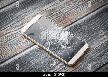 Rotto moderno mobile phone su sfondo di legno. Foto Stock