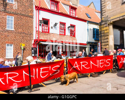 Turisti che si godono una sosta e ristoro presso i tavoli fuori Arnie's Bistro Café in luogo di mercato Whitby North Yorkshire Foto Stock