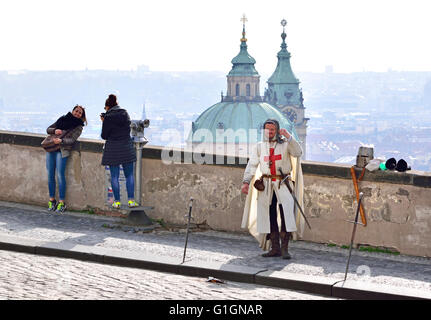 Praga, Repubblica Ceca. Uomo vestito come un cavaliere medievale in Hradcanske namesti - St Nicholas' Chiesa dietro Foto Stock