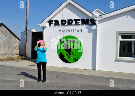 Donna prendendo selfie a veletta dell'Irlanda più settentrionali pub a Malin Head, County Donegal, Irlanda. Foto Stock