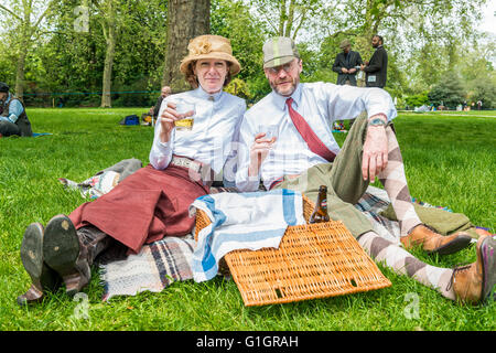 London, Regno Unito - 14 Maggio 2016: Tweed Run (corsa in bicicletta con uno stile) a pic-nic nei pressi Albert Memorial a Kensington Gardens e Hyde Park. Una bellissima giovane sta avendo un picnic sull'erba Credito: Elena Chaykina/Alamy Live News Foto Stock