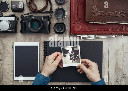 Attrezzature fotografiche, fotocamere digitali e PC tablet su un desktop vintage, un fotografo è creare il suo album di foto Foto Stock