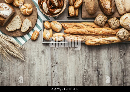 Pane appena sfornato delizioso pane su un rustico di piano di lavoro in legno con copia spazio, mangiare sano concetto, laici piatta Foto Stock