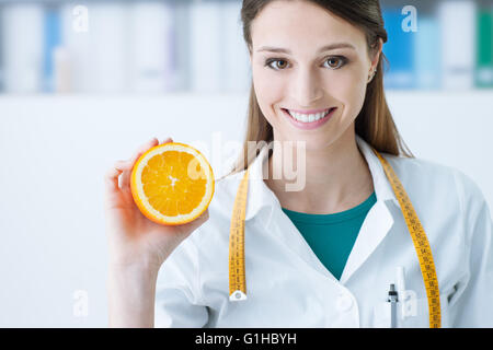 Sorridente nutrizionista tenendo un fette di arancia, vitamine e dieta sana nozione Foto Stock