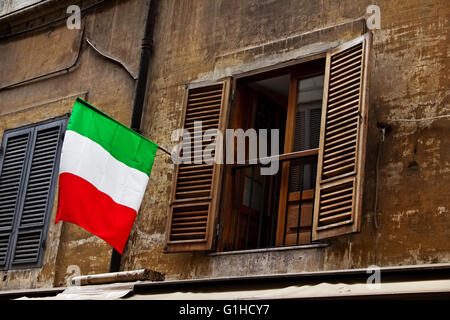 Finestra aperta con la bandiera italiana sulla facciata del vecchio edificio in Roma, Italia Foto Stock