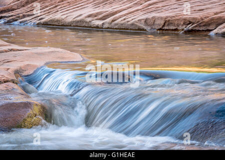 Piccolo ruscello che scorre e cascata su formazioni di arenaria - Mill Creek, Moab, Utah Foto Stock