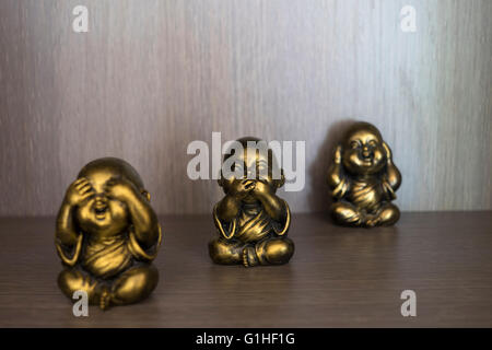 Tre saggi Buddha vedere sentire parlare Nessun male statua contro lo sfondo di legno Foto Stock