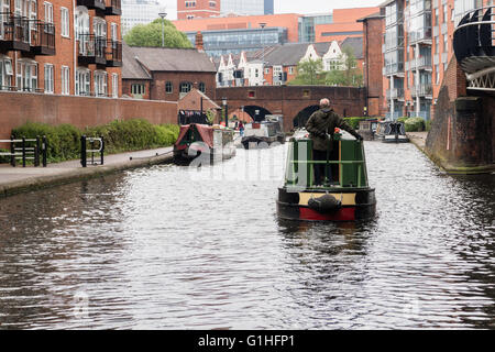 Un uomo manzi il suo narrowboat verso Birmingham City Centre Foto Stock