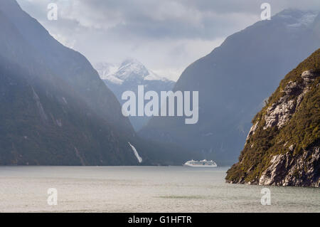 Milford Sound, Nuova Zelanda - 14 Novembre 2014: Milford Sound in un giorno di pioggia. Lo splendore del mare la nave di crociera nella parte posteriore Foto Stock