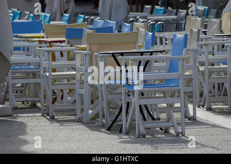 Primo piano su una fila di myconos-colore blu dipinto di sedie vuote & caffe tavoli. La Grecia. Foto Stock