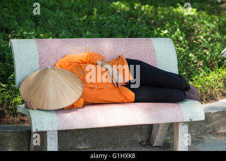 Donna asiatica di dormire su una panchina nel parco in day time, Hanoi Foto Stock